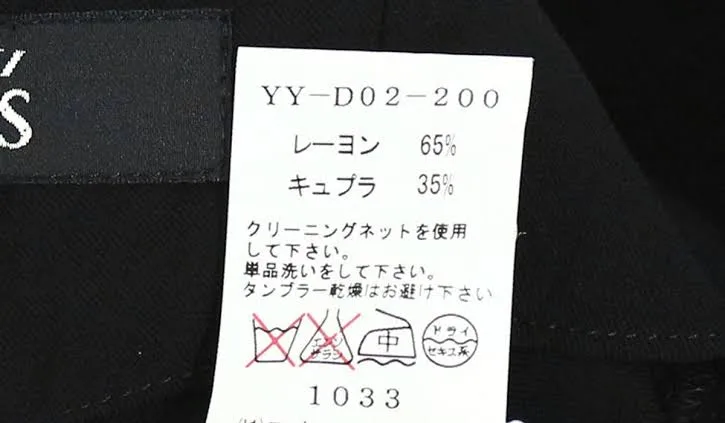 Yohji Yamamoto care label printed YY-D02-200 above rayon 65% and cupro 35% in katakana, Japanese washing instructions, care symbols and the number 1033, beside a black neck label